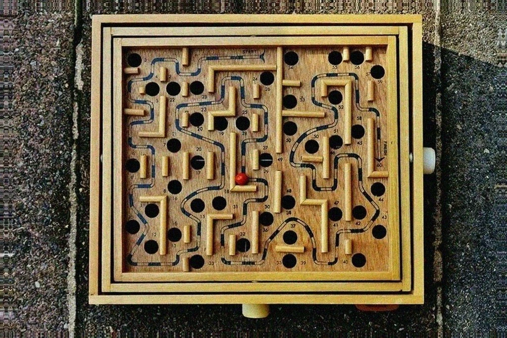A real wooden tilt maze board with a red ball, holes, and start and finish labels