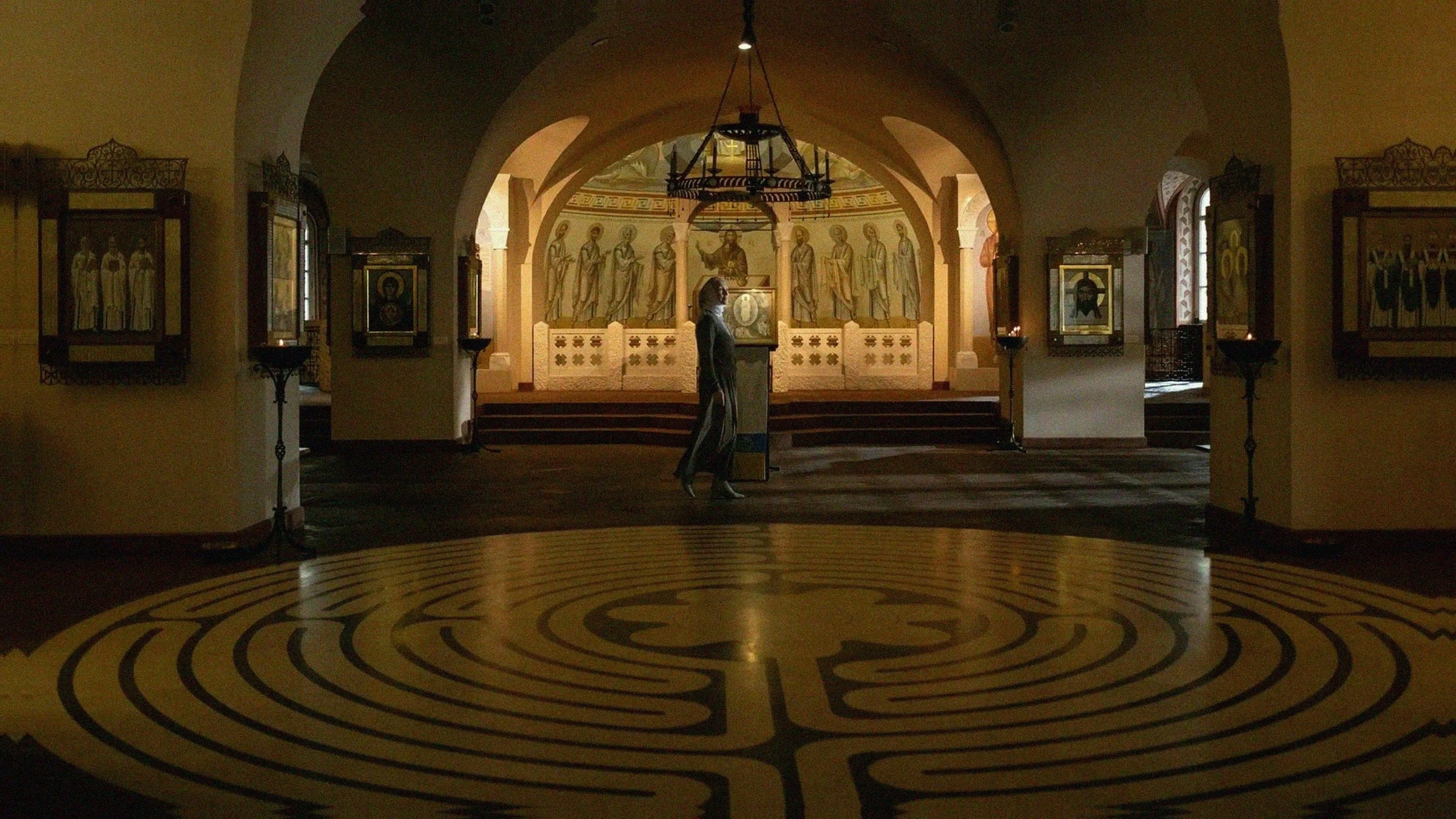 Woman walking across a floor labyrinth inside an ornate Orthodox church