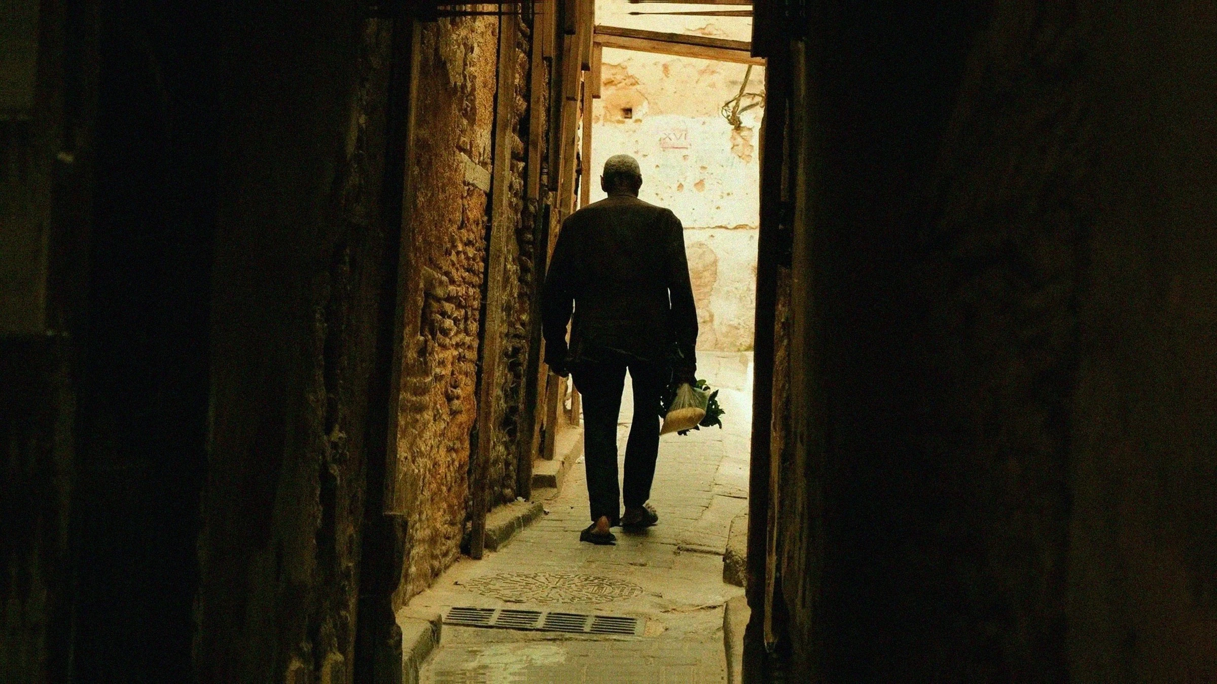 Man carrying flowers through a narrow passage in Fes Medina, Morocco